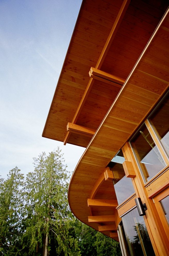 Modelo de fachada marrón rural de tamaño medio de dos plantas con revestimiento de madera y tejado plano