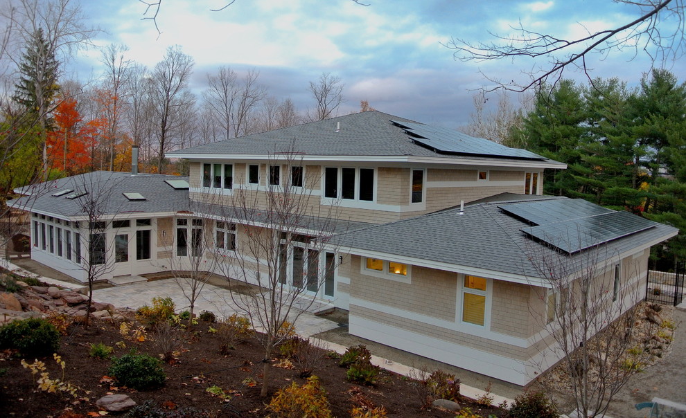Cette image montre une grande façade de maison beige design en bois à un étage avec un toit à quatre pans.