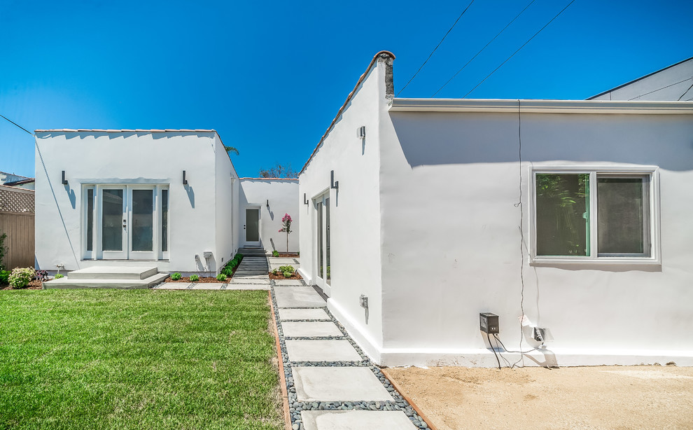Diseño de fachada de casa blanca contemporánea de tamaño medio de una planta con revestimiento de estuco, tejado a dos aguas y tejado de teja de barro