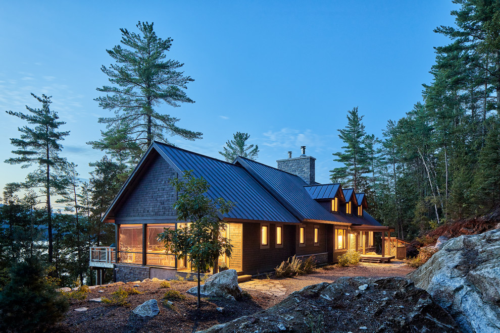 Aménagement d'une grande façade de maison marron montagne en bois à niveaux décalés avec un toit à deux pans et un toit en métal.