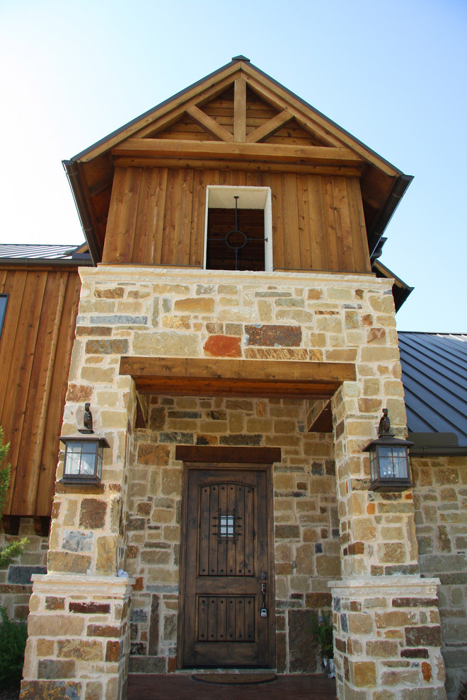 Design ideas for a large rustic two floor house exterior in Dallas with stone cladding.