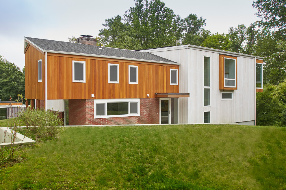 Свежая идея для дизайна: двухэтажный, деревянный, разноцветный частный загородный дом среднего размера в стиле модернизм с односкатной крышей и крышей из смешанных материалов - отличное фото интерьера