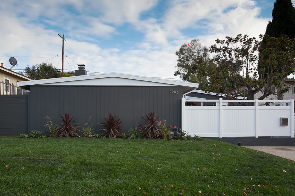 На фото: одноэтажный, серый дом в стиле ретро с двускатной крышей с