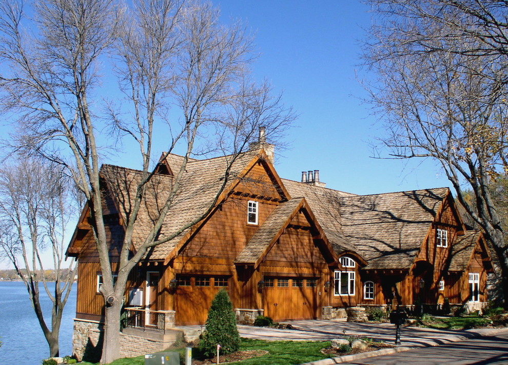 This is an example of a large and brown rustic two floor house exterior in Minneapolis with wood cladding and a pitched roof.