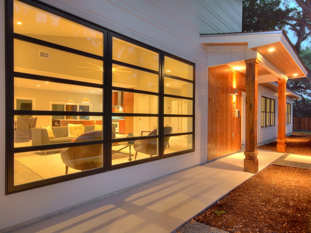 White midcentury bungalow house exterior in Austin with wood cladding and a lean-to roof.