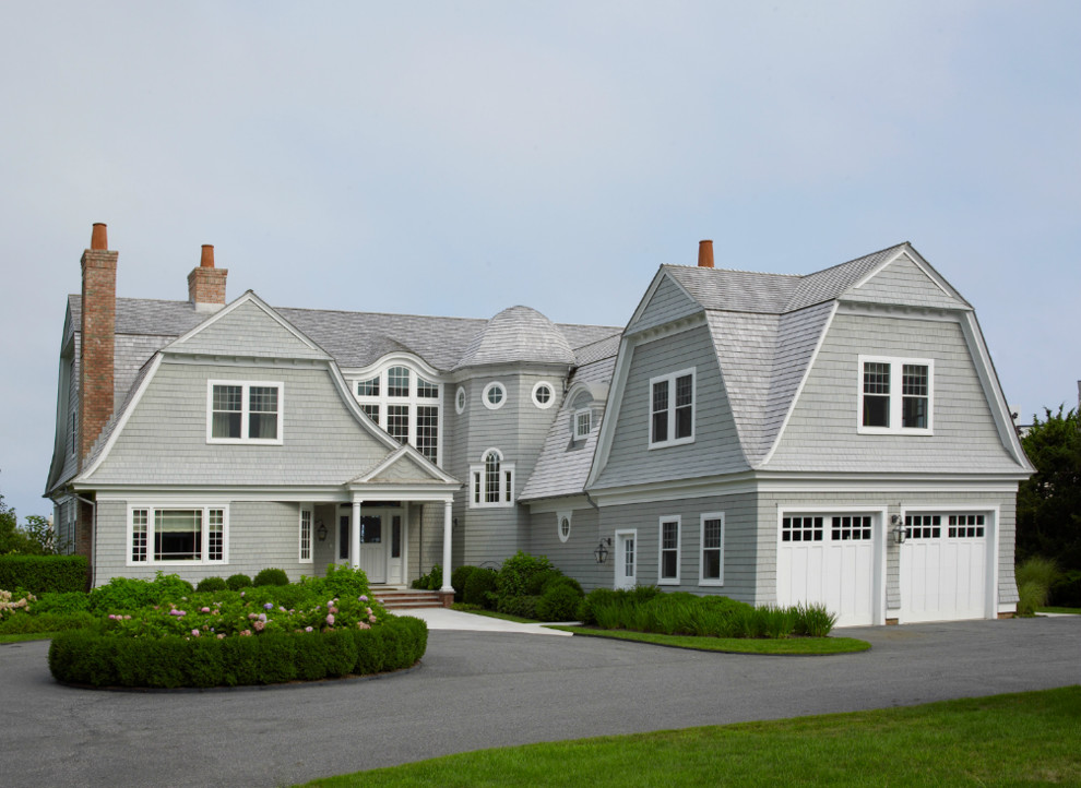 Gey beach style two floor detached house in New York with wood cladding, a mansard roof and a shingle roof.