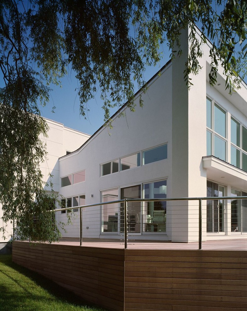 Idées déco pour une façade de maison blanche moderne en stuc de taille moyenne et à niveaux décalés avec un toit en appentis.
