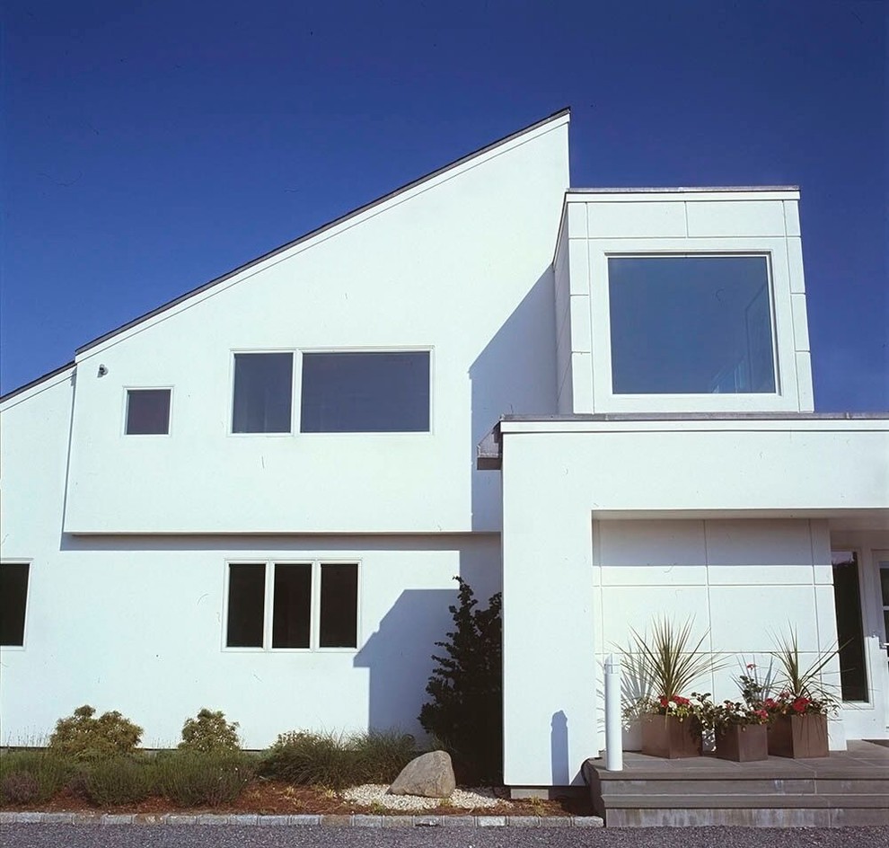 Bild på ett mellanstort funkis vitt hus i flera nivåer, med stuckatur och pulpettak