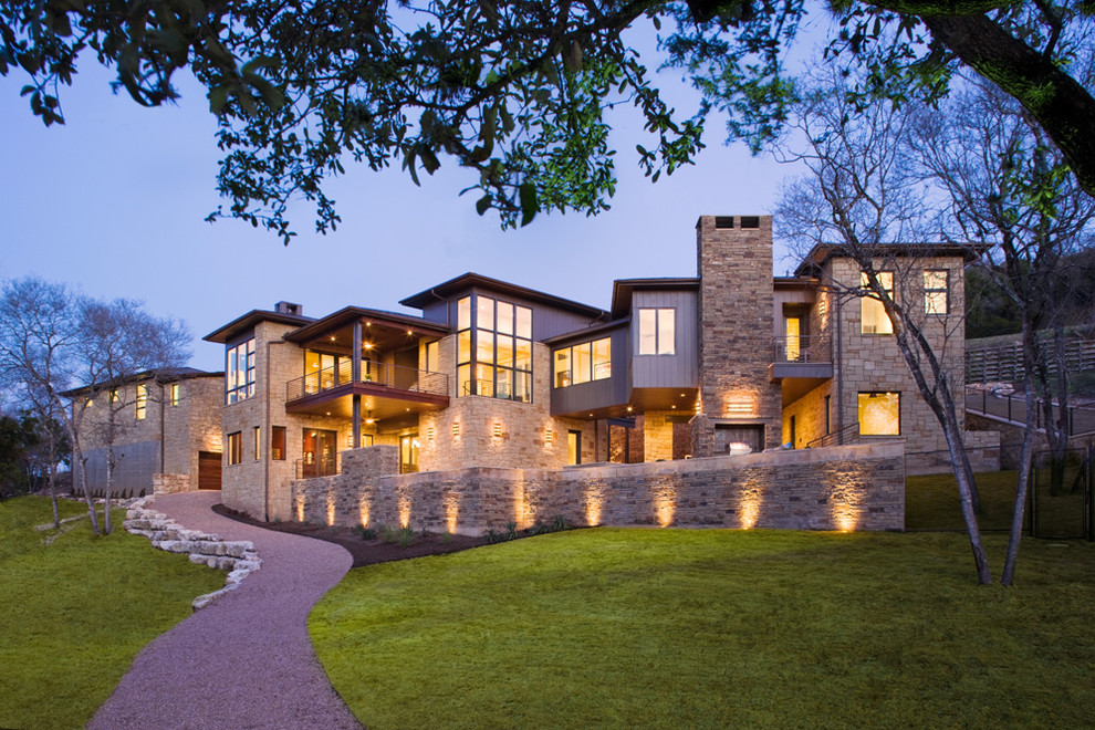Example of a huge trendy beige two-story stone exterior home design in Austin with a metal roof