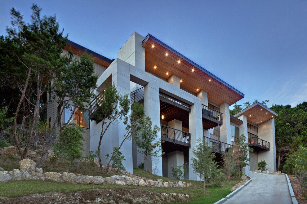This is an example of a gey contemporary split-level concrete house exterior in Austin.