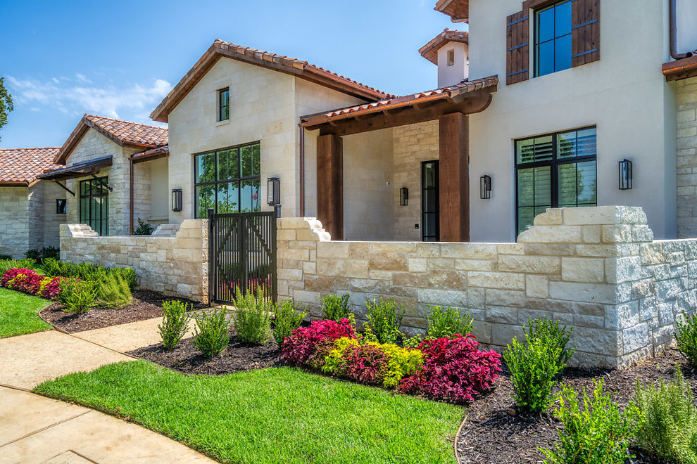 Example of a large transitional gray one-story stone house exterior design in Dallas with a hip roof and a tile roof