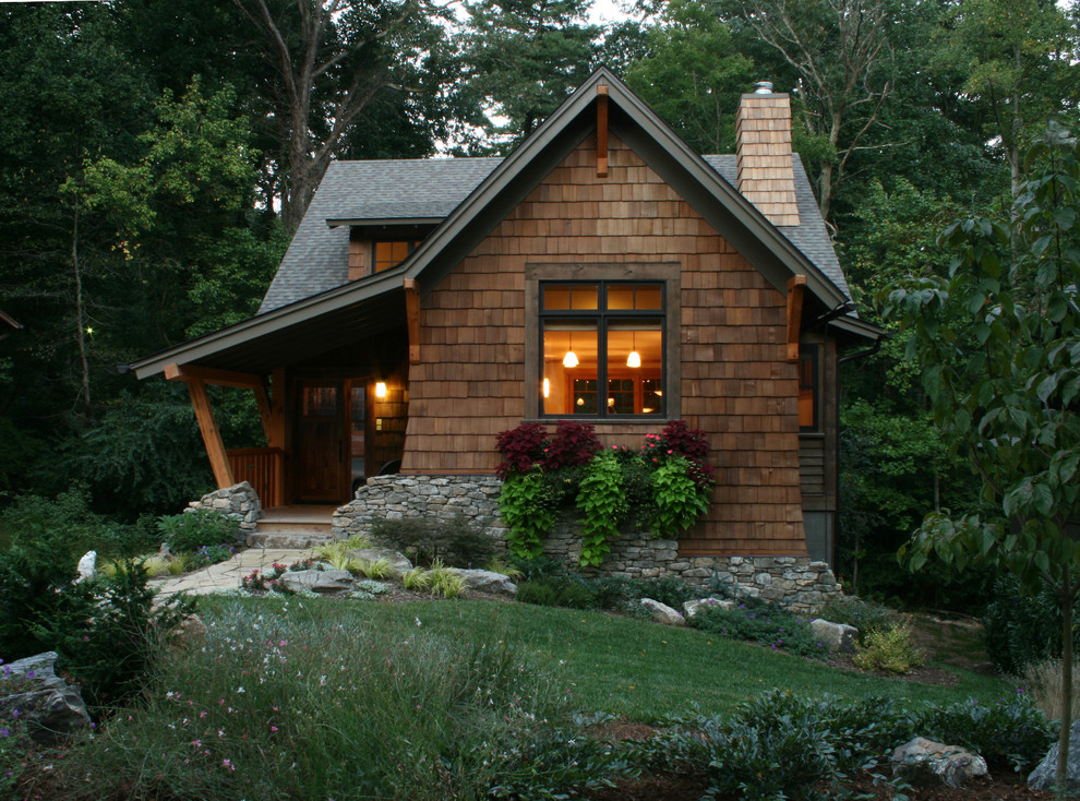 Foto della facciata di una casa piccola marrone rustica a due piani con rivestimento in legno e tetto a capanna