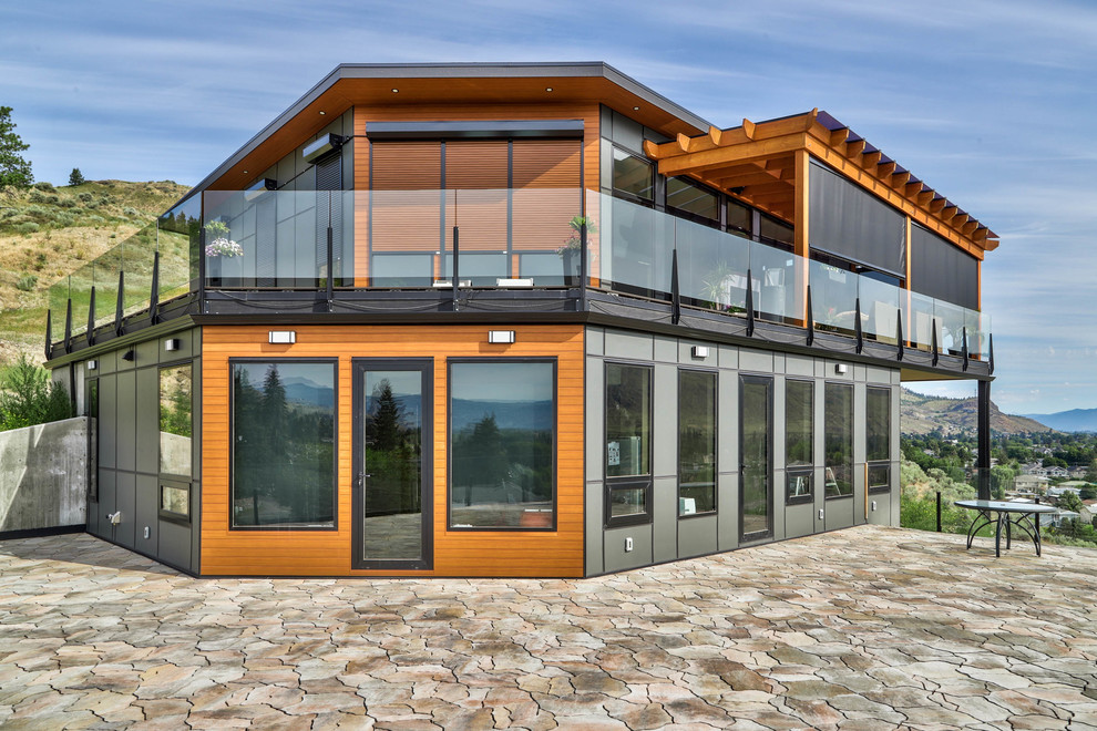 Diseño de fachada de casa gris actual grande a niveles con revestimientos combinados, tejado plano y tejado de metal