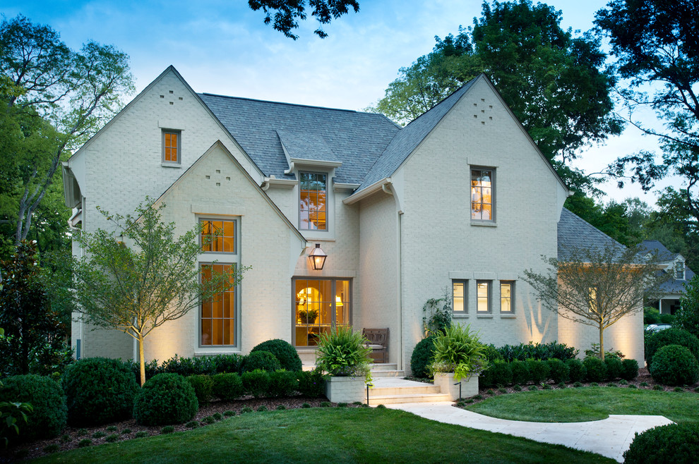 Imagen de fachada beige clásica grande de dos plantas con revestimiento de ladrillo y tejado a dos aguas