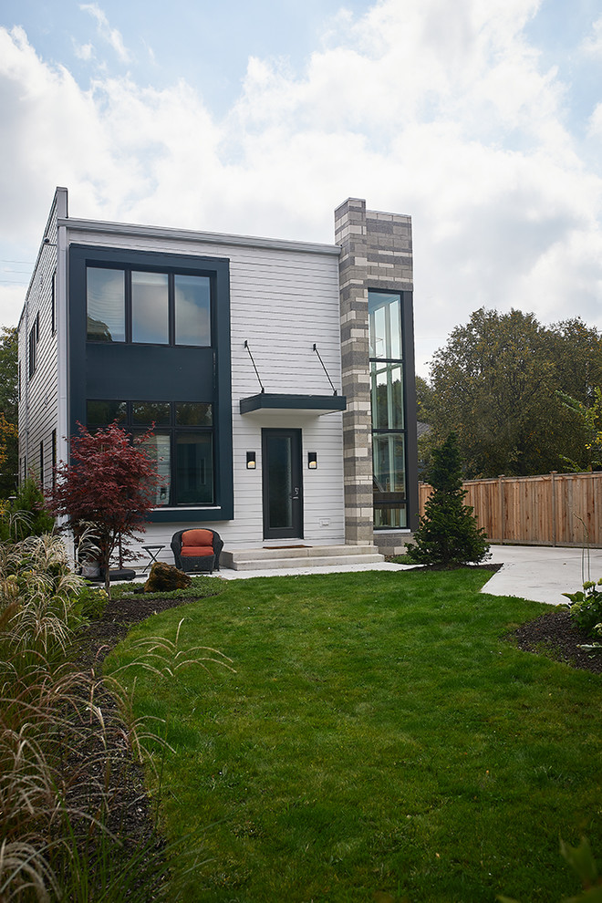 Inspiration for a small contemporary white two-story brick exterior home remodel in Grand Rapids with a shingle roof