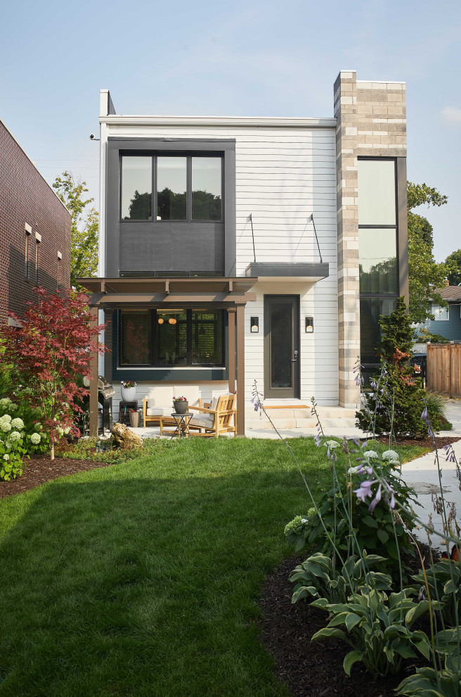 Cette image montre une façade de maison multicolore design en panneau de béton fibré de taille moyenne et à un étage avec un toit plat.