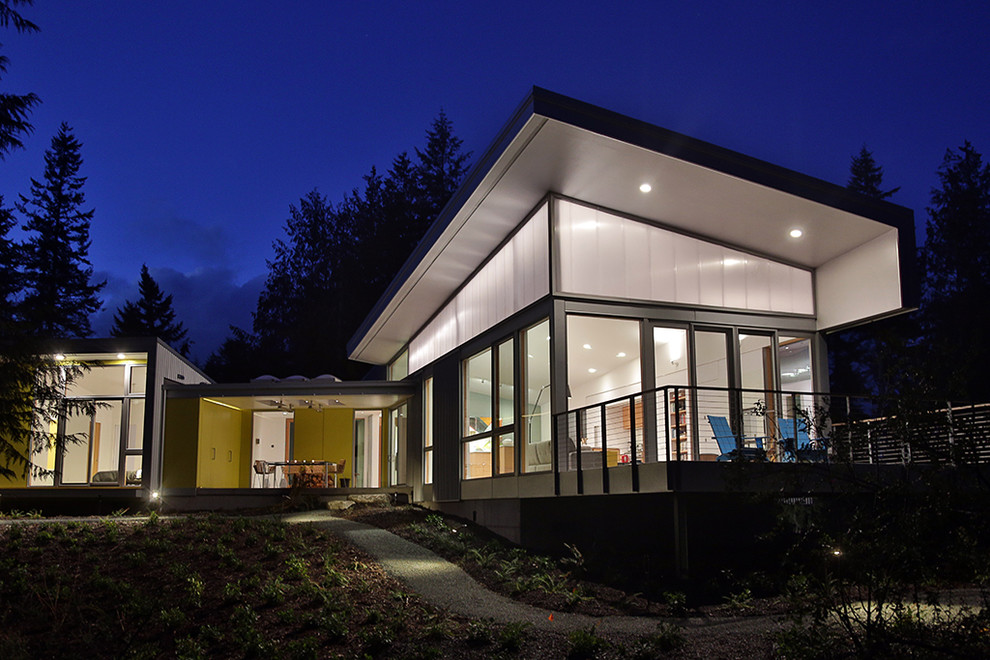 Example of an urban yellow one-story mixed siding house exterior design in Seattle with a shed roof and a metal roof