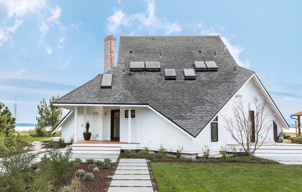 Aménagement d'une façade de maison blanche bord de mer en bois à un étage avec un toit à quatre pans.