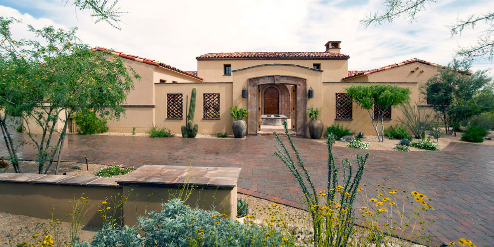 This is an example of a large and beige mediterranean bungalow render house exterior in Phoenix.