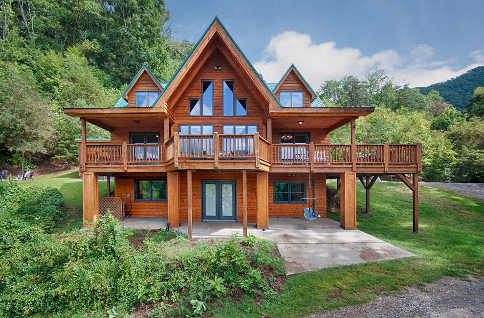 Large mountain style brown three-story wood exterior home photo in Other