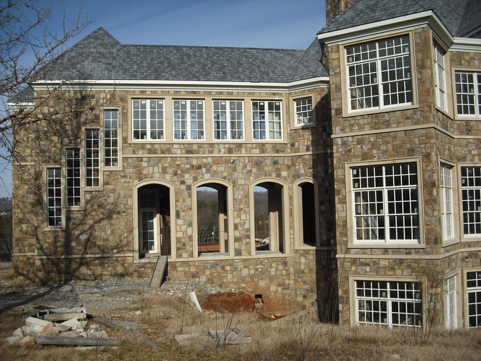 Ejemplo de fachada de casa marrón clásica grande de tres plantas con revestimiento de piedra y tejado de teja de madera