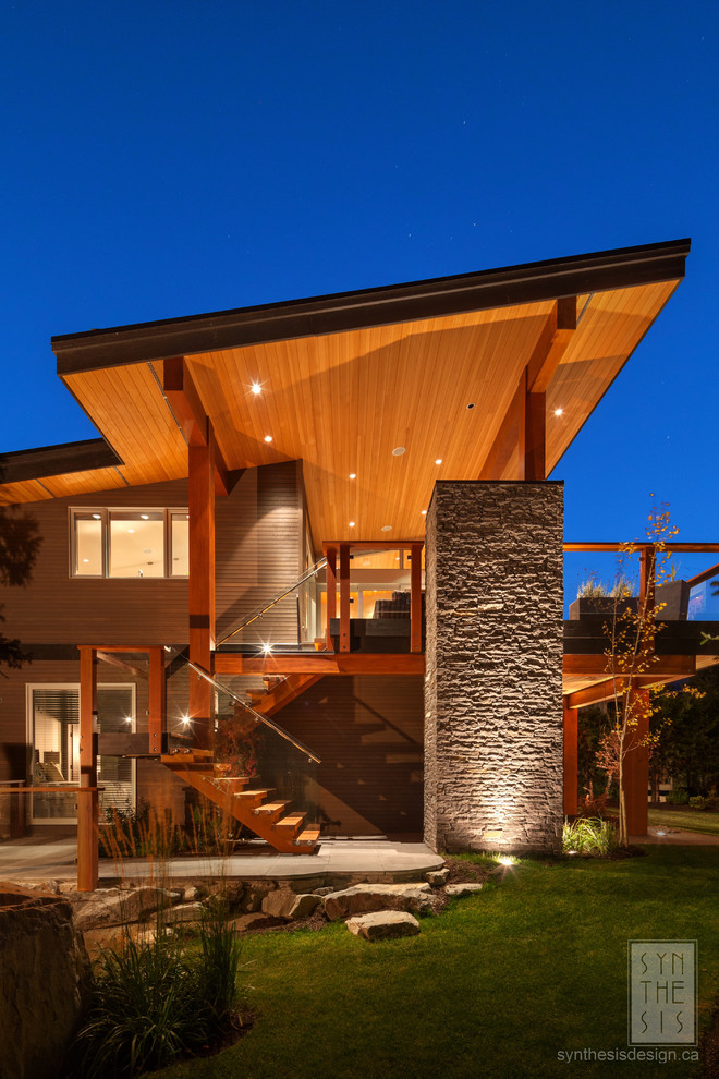 Стильный дизайн: большой, двухэтажный, коричневый частный загородный дом в современном стиле с комбинированной облицовкой и плоской крышей - последний тренд