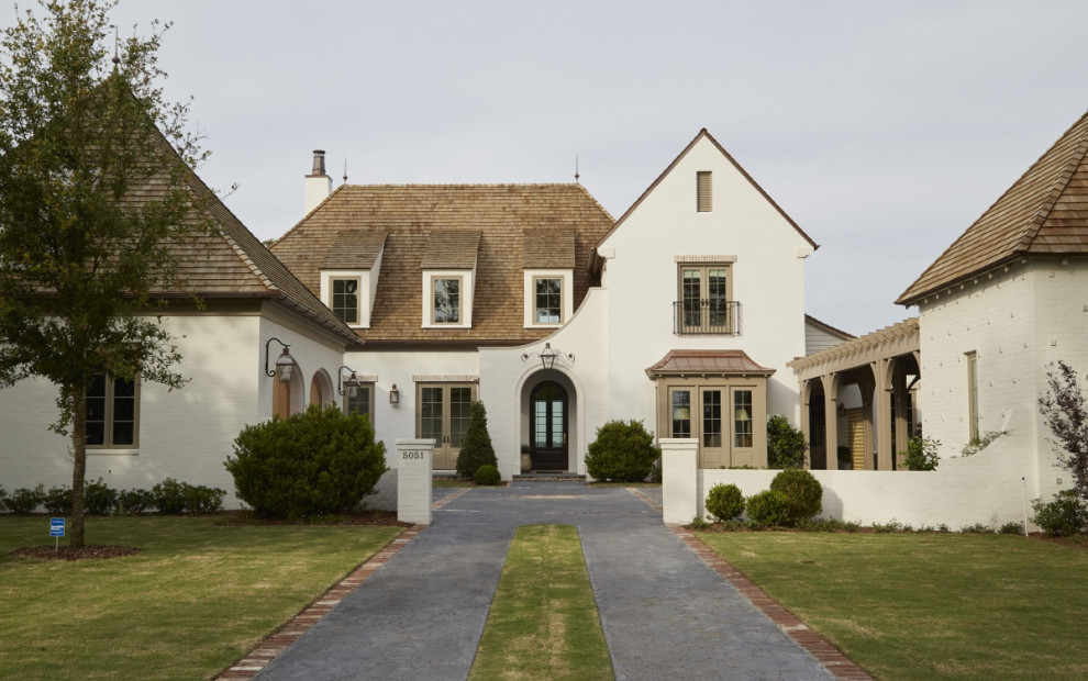 Large french country white two-story brick house exterior photo in Jacksonville with a shingle roof