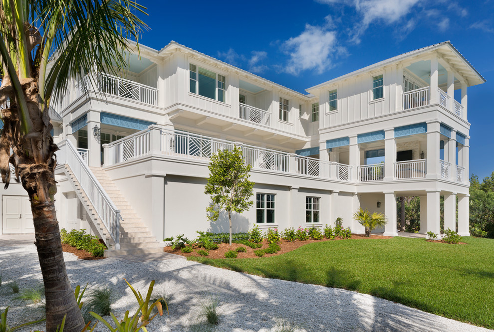 Inspiration for a large tropical white two-story stucco house exterior remodel in Miami with a tile roof