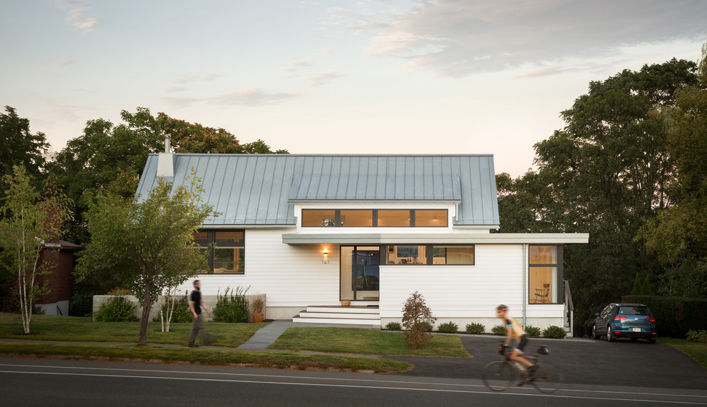 Cette photo montre une façade de maison blanche tendance de plain-pied avec un toit à deux pans et un toit en métal.
