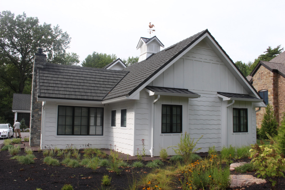 Immagine della villa ampia bianca moderna a due piani con rivestimento in legno, tetto a capanna e copertura in tegole