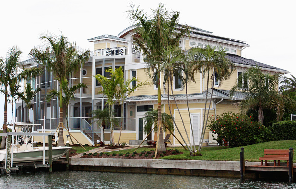 Пример оригинального дизайна: огромный, трехэтажный, желтый дом в морском стиле с комбинированной облицовкой и вальмовой крышей