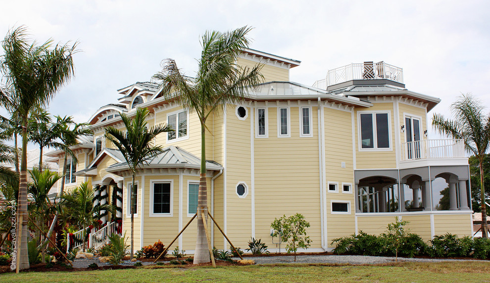 Идея дизайна: огромный, трехэтажный, желтый дом в морском стиле с комбинированной облицовкой и вальмовой крышей