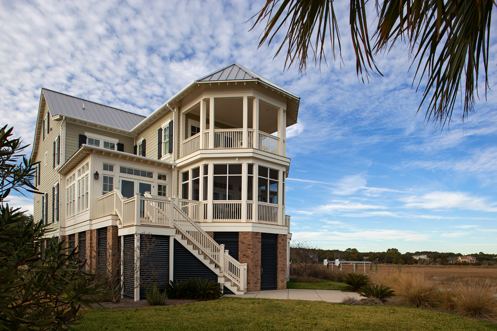 Aménagement d'une grande façade de maison beige bord de mer en bois à deux étages et plus avec un toit à deux pans.