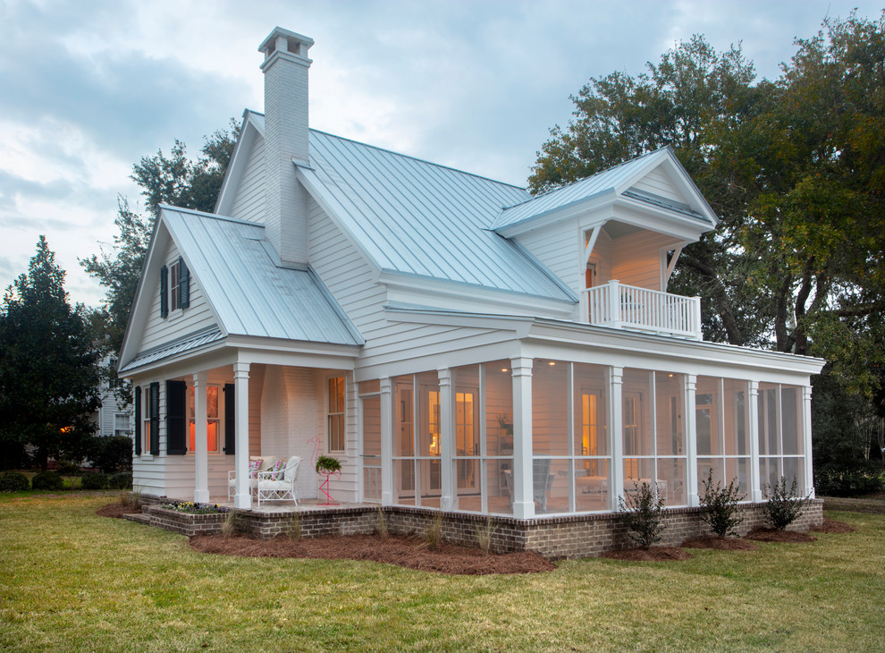 Imagen de fachada de casa blanca marinera de dos plantas con tejado a dos aguas y tejado de metal