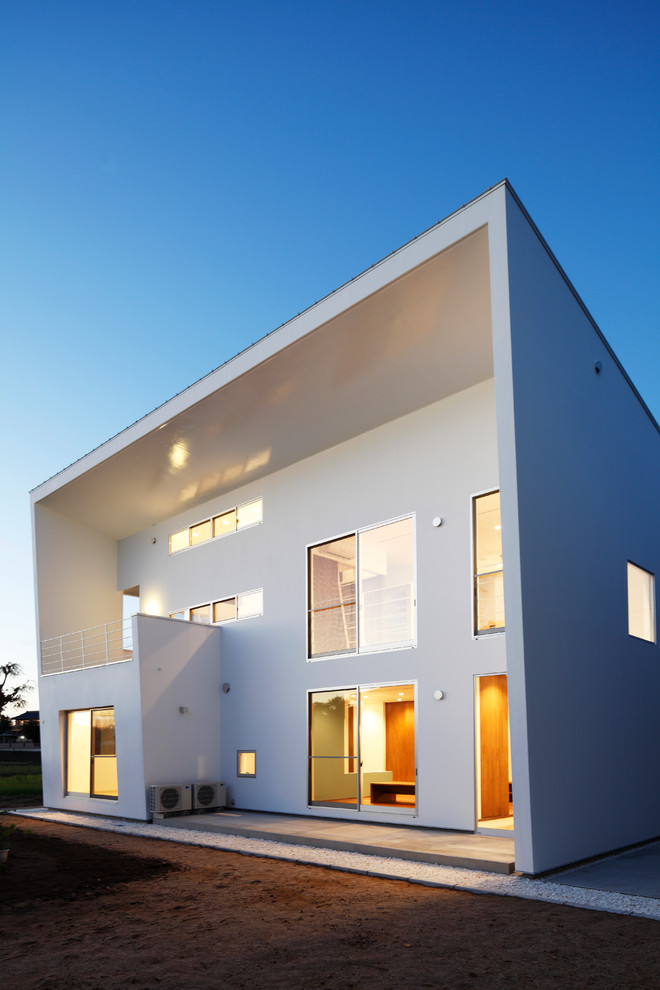 Foto della villa bianca contemporanea a due piani con rivestimento in cemento e tetto piano