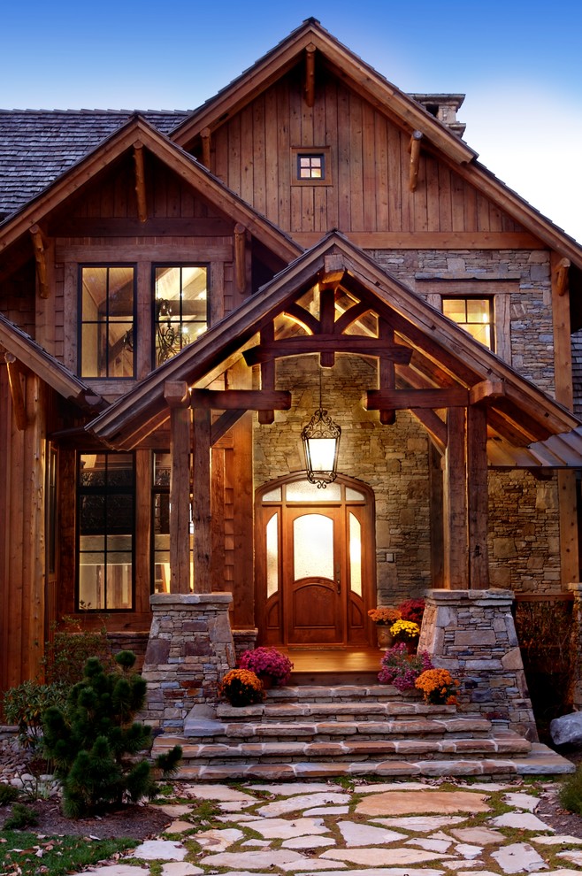 Immagine della facciata di una casa ampia marrone rustica a due piani con rivestimento in legno e tetto a capanna