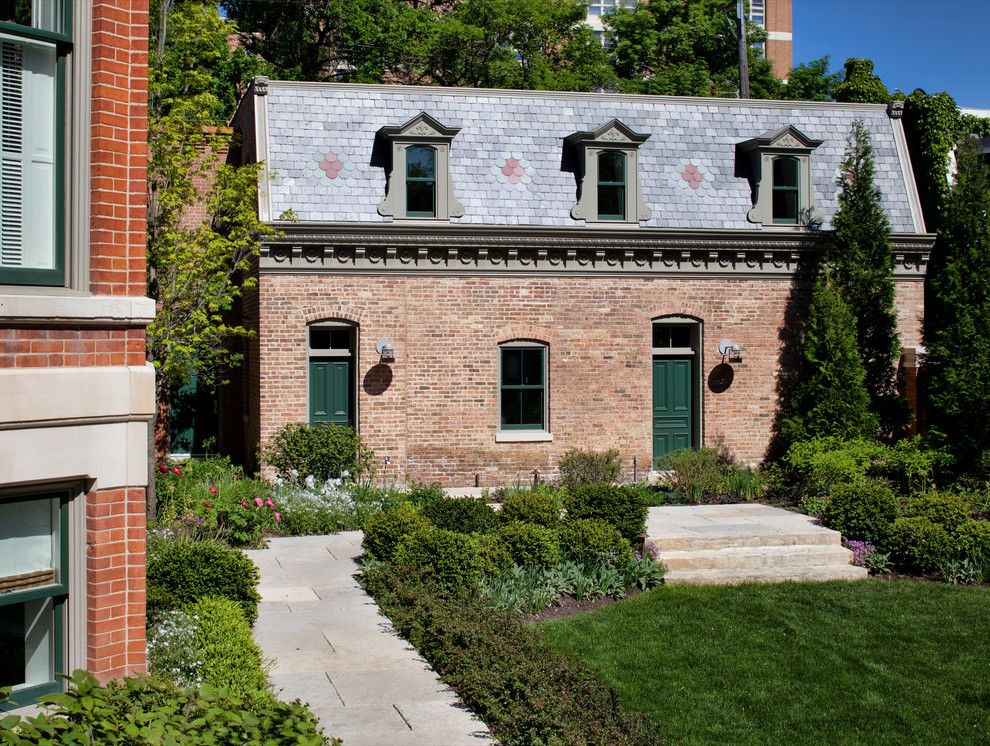 Foto de fachada de casa roja clásica de dos plantas con revestimiento de ladrillo y tejado de teja de barro