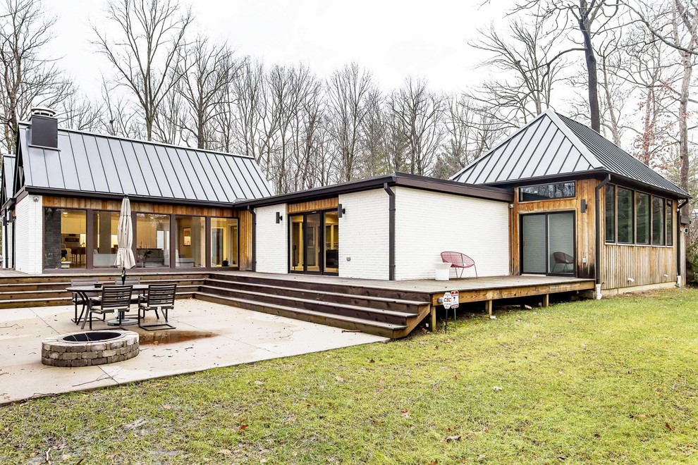 Cette image montre une grande façade de maison blanche minimaliste en brique de plain-pied avec un toit en métal.