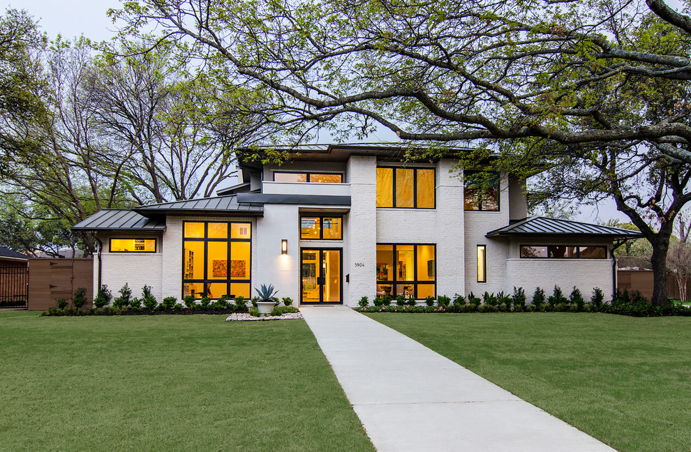 Example of a large trendy white two-story brick exterior home design in Dallas with a hip roof