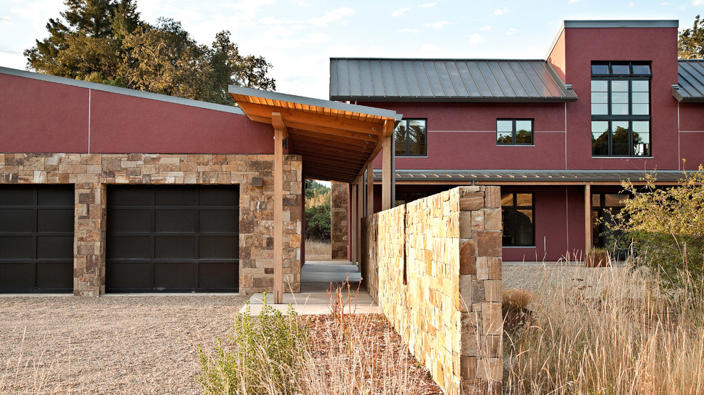 Idée de décoration pour une grande façade de maison rouge design en stuc à un étage avec un toit en métal.