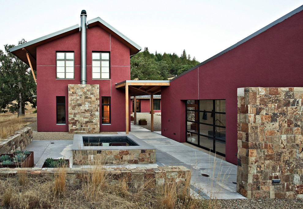 Diseño de fachada de casa roja actual grande de dos plantas con revestimiento de estuco y tejado de metal