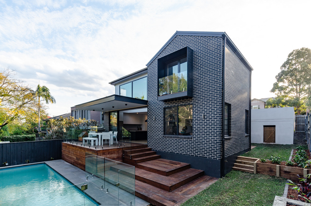 Пример оригинального дизайна: двухэтажный, кирпичный, черный, большой частный загородный дом в современном стиле с двускатной крышей и металлической крышей