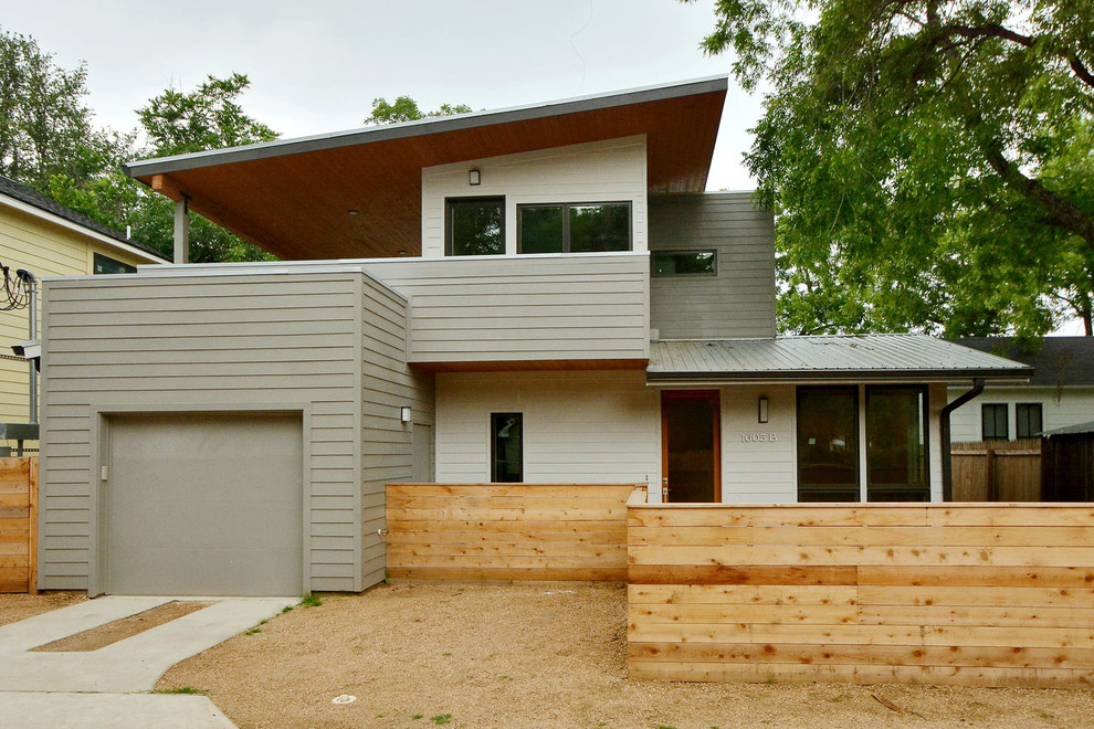 Idée de décoration pour une petite façade de maison grise minimaliste en panneau de béton fibré à un étage avec un toit en appentis et un toit en métal.
