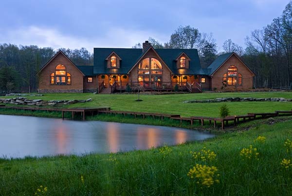 На фото: большой, двухэтажный, деревянный, коричневый дом в стиле рустика с двускатной крышей для охотников