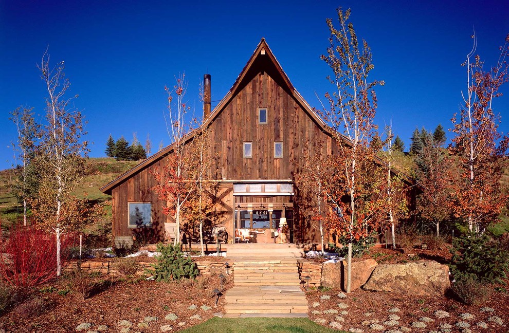 Inspiration for a rustic two floor house exterior in Denver with wood cladding.