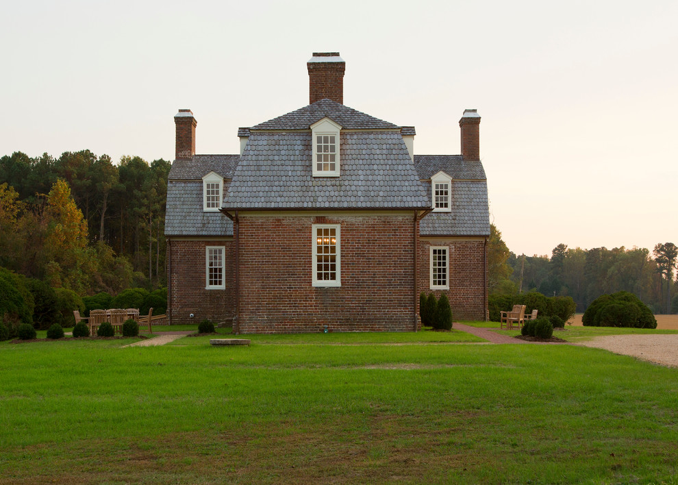 Esempio della facciata di una casa ampia rossa country a due piani con rivestimento in mattoni e tetto a mansarda