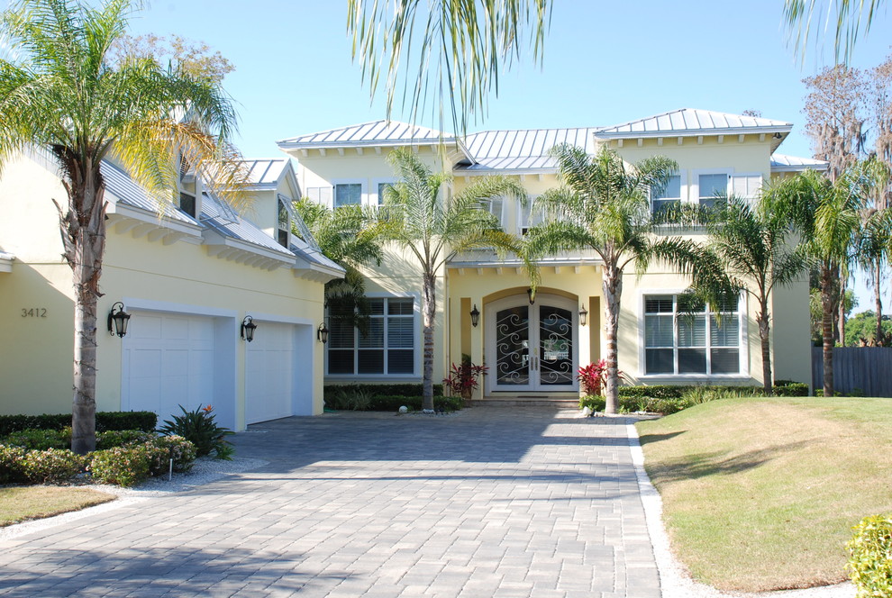 Large tropical yellow two-story stucco gable roof idea in Orlando
