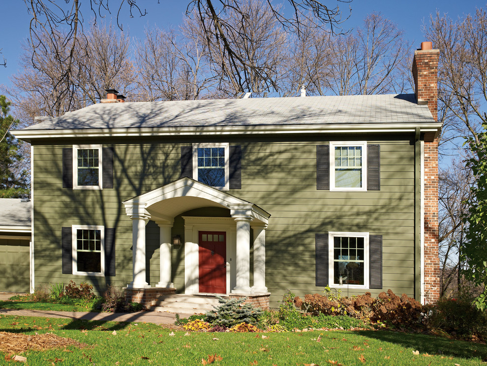 Modelo de fachada de casa verde de estilo americano de tamaño medio de dos plantas con revestimiento de vinilo, tejado a dos aguas y tejado de teja de barro