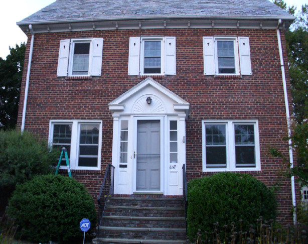 Example of a large classic red two-story brick gable roof design in New York
