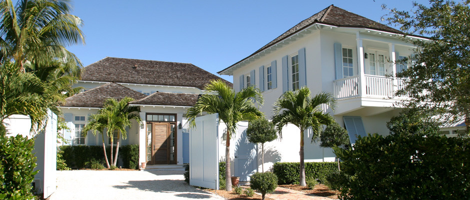 Bild på ett stort tropiskt vitt hus, med två våningar, stuckatur och halvvalmat sadeltak
